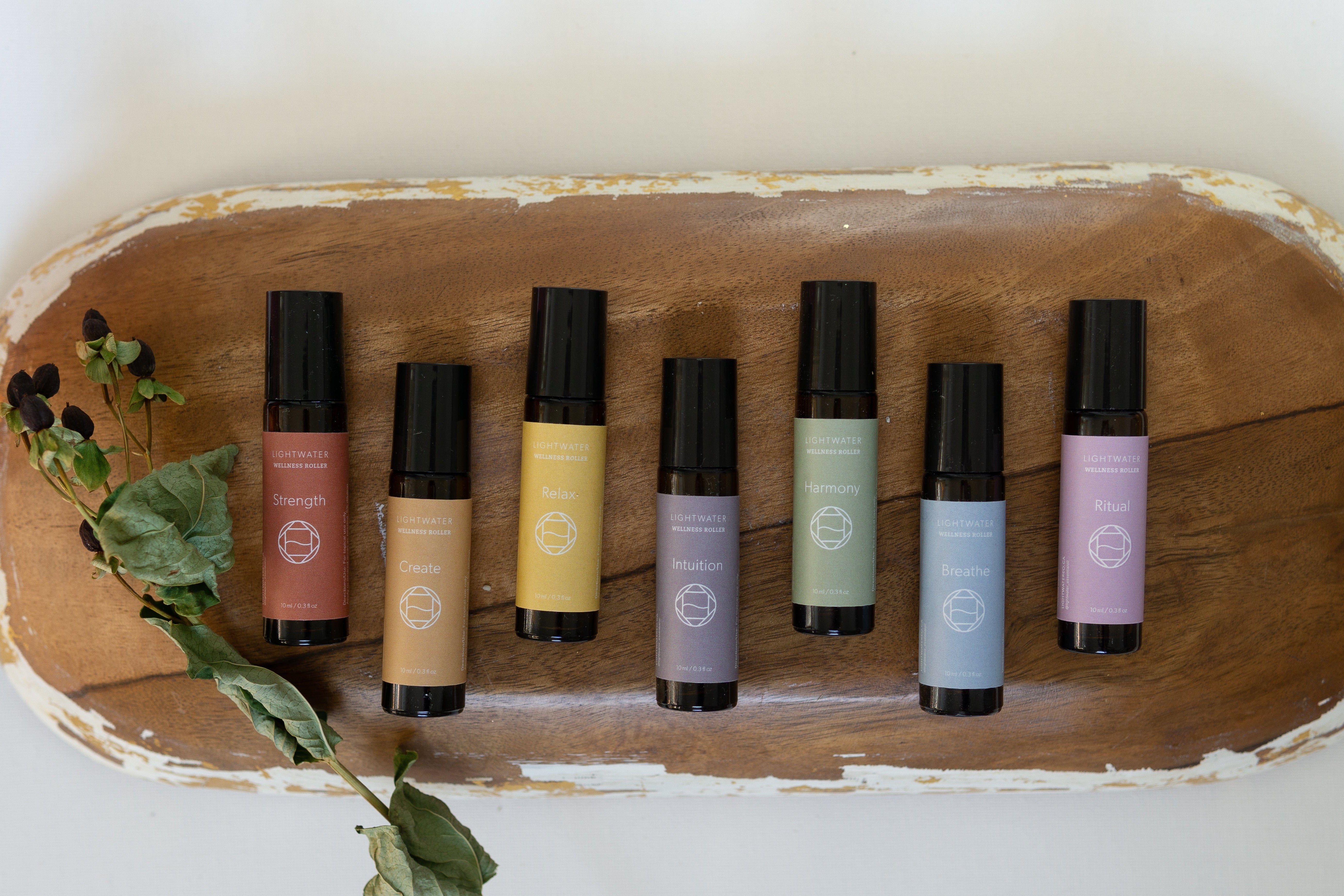 Set of roller bottles with colorful labels on a wooden tray.